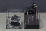 Micah Schippa-Wildfong, <em>A snake whose mouth is perfect (7 scenes produced remotely)</em>, antique Kodak Agfa Ansco box camera, sheet music ash, various light fixtures & bulbs, decanter with iodine, super8 film viewer, quartz clock movement mechanism & clock hands, various glassware, photograph of soldiers, glue, salt, saltwater, lacrimal solution (false tears formulated by the artist), red vermouth, lighting dimmer, typewriter, ink, speakers, doorhandle, thermometer parts (all objects found), dimensions variable, 2026 – Thumbnail preview