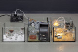 Micah Schippa-Wildfong, <em>A snake whose mouth is perfect (7 scenes produced remotely)</em>, antique Kodak Agfa Ansco box camera, sheet music ash, various light fixtures & bulbs, decanter with iodine, super8 film viewer, quartz clock movement mechanism & clock hands, various glassware, photograph of soldiers, glue, salt, saltwater, lacrimal solution (false tears formulated by the artist), red vermouth, lighting dimmer, typewriter, ink, speakers, doorhandle, thermometer parts (all objects found), dimensions variable, 2026 – Thumbnail preview